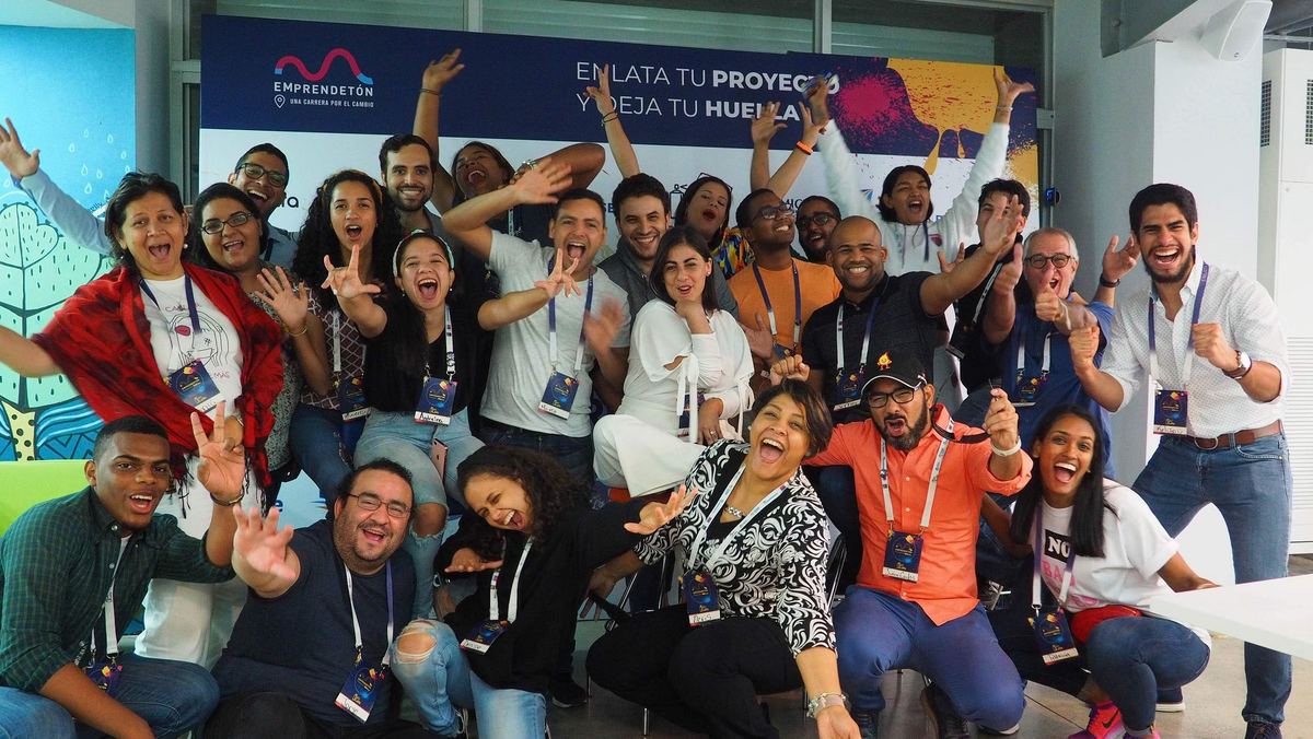 Un grupo grande de emprendedores dominicanos celebra con los brazos en alto al cierre de una actividad de Fundación Enlata