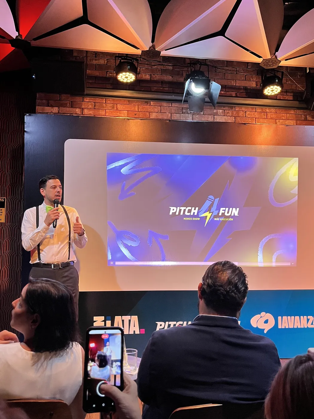 Emprendedor presentando su proyecto en tarima frente a la pantalla del evento
